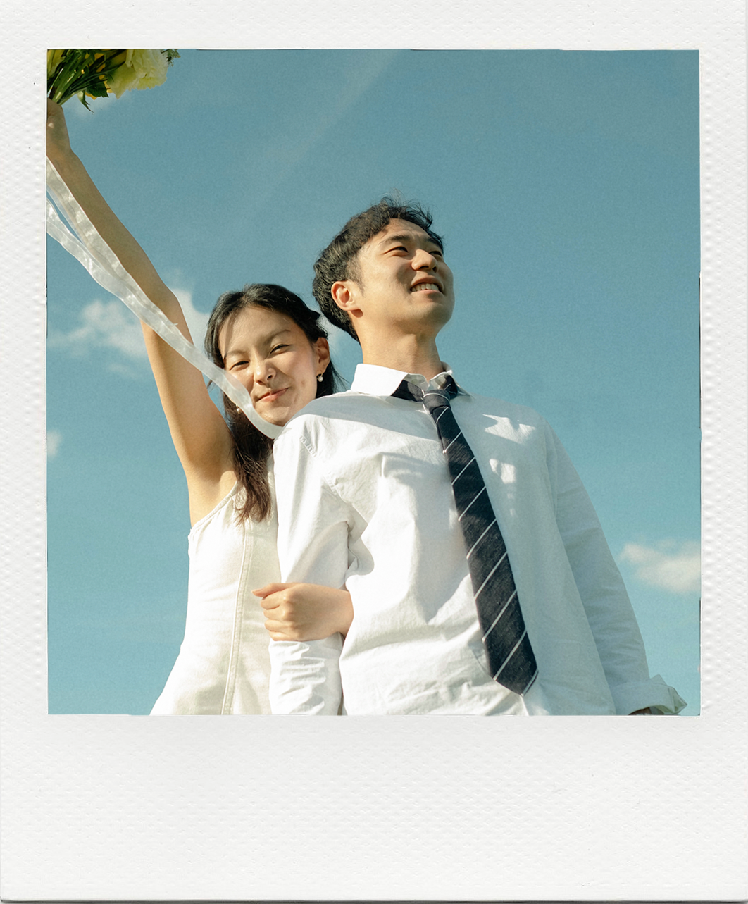 Daniel and Hoyeon beneath a blue sky in a Polaroid frame
